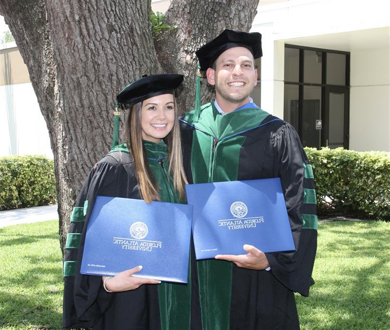 Dr. Kenan Ashouri and Dr. Annie Lopez-Ashouri at graduation posing with diplomas